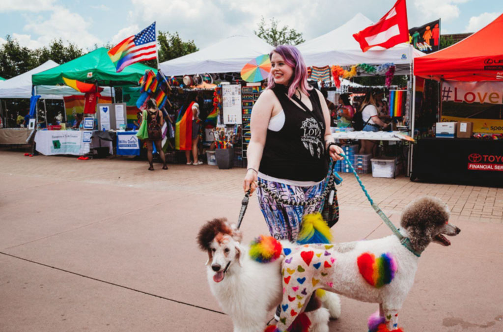 A NewBo City Market visitor leads two dogs decked in rainbow colors.
